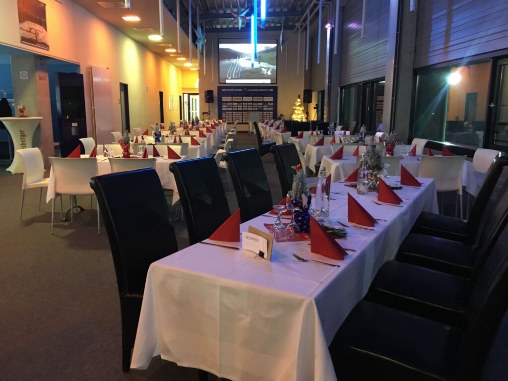 Lange Tafel mit weißen Tischdecken und roten Servietten